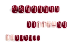 Detail of burgundy press-on nails with plaid patterns, bows and sparkling rhinestones