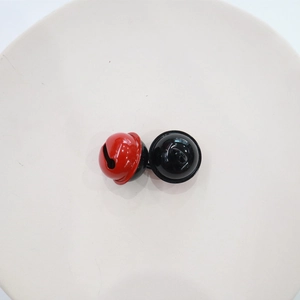 Close-up of dual-tone red and black 2.2cm metal bells on a white ceramic plate