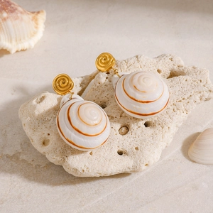 Golden spiral stud earrings with natural nautilus shell pendants on coral stone