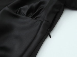 Close-up of black satin shirt detailing smooth fabric texture and hidden side zipper