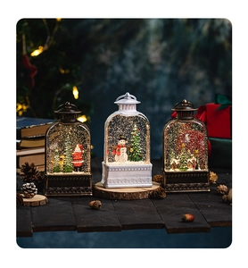 Three bronze and white Christmas snow globe lanterns on a wooden desk with festive LED lights