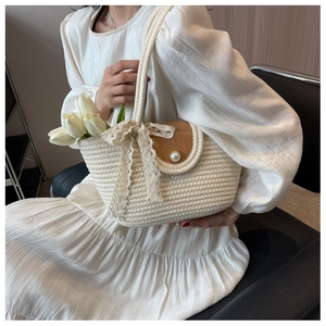Beige woven beach tote with brown leather flap, pearl clasp, and decorative lace bow