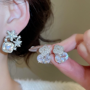 Détail macro de boucles d'oreilles en argent avec fleurs en zircon et cristaux carrés