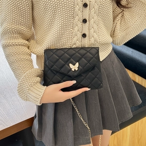 Chic black quilted crossbody bag with white butterfly buckle and gold chain strap