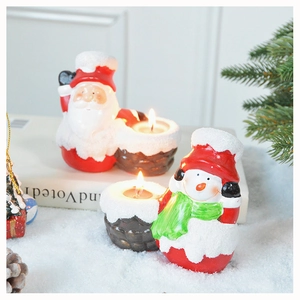 Detailed view of Santa and Snowman ceramic candle holders in a festive winter scene