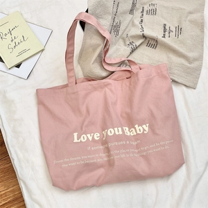 Detail of pink canvas tote bag with Love you Baby print on a soft cotton background