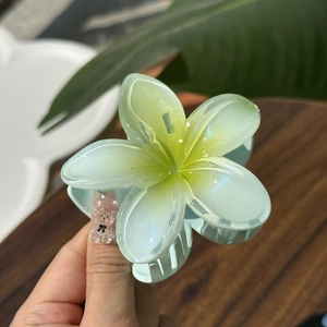 Macro shot of mint green jelly frangipani flower hair claw clip with subtle glitter