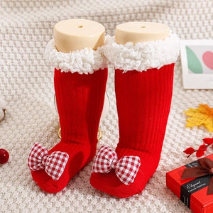 Detail of red Christmas baby socks with plush white fleece cuffs and checkered bow knots