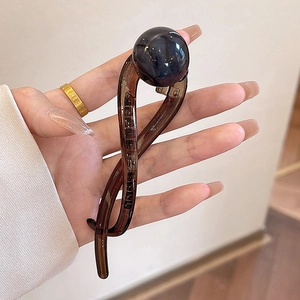Detail of s-shaped hair clip in dark brown with a large polished black bead decoration