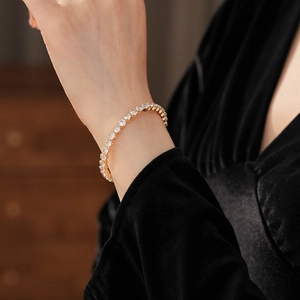 Close-up of gold tennis bracelet with white cubic zirconia worn on a model wrist