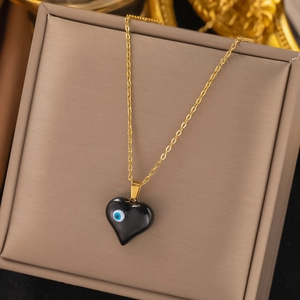 Golden necklace with black heart pendant featuring blue evil eye charm and O-chain