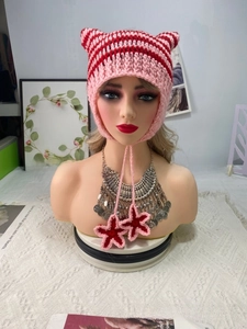 Close-up of pink and red striped crochet hat with cat ears and star charms
