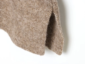 Detailed macro shot of the split side hem on this camel brown knit wool sweater