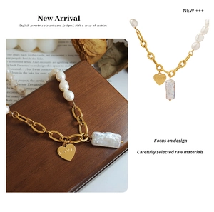 Macro view of 18K gold-plated chunky chain with heart charm and baroque pearls