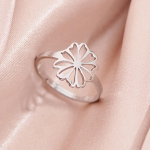 Adjustable silver stainless steel ring with hollow daisy design on pink silk background