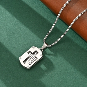 Detail showing a silver cross pendant with grid texture and box chain necklace