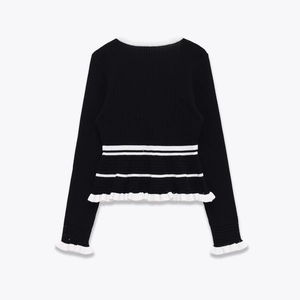 Women's black rib-knit sweater featuring white contrast ruffle trim and back detail