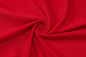 Macro shot of soft red fabric texture with a spiral fold pattern showing fine knit details