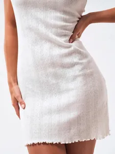 Close-up of white pointelle knit mini dress with delicate floral texture and lettuce edge hem