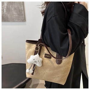 Detail of khaki suede tote bag with brown straps and white cloud smiley charm pendant
