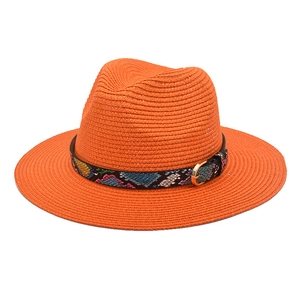Detail of bright orange straw fedora with colorful snakeskin band and metal buckle