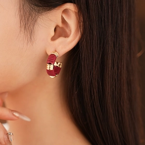 Dettaglio dell'orecchino a C in pelle intrecciata bordeaux con accento dorato elegante