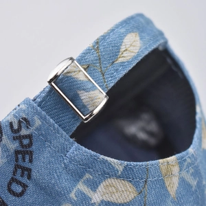Detail of adjustable metal buckle on blue denim baseball cap with SPEED print