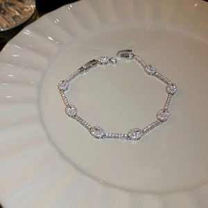 Detailed shot of silver zircon bracelet with oval crystals on a white ceramic plate
