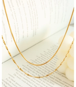 Close-up of golden titanium steel double-layer flat snake and twisted wave necklaces