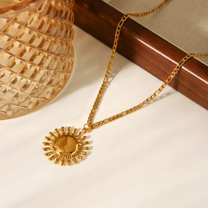Gros plan du collier avec pendentif soleil en or 18 carats sur plateau en bois
