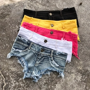 Vista piatta di pantaloncini di jeans a vita bassa colorati con orli grezzi su pietra