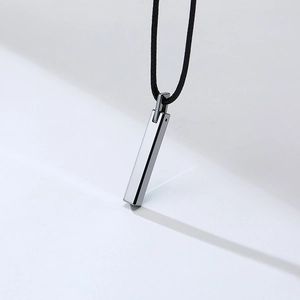 Close-up of a silver-toned polished tungsten bar pendant on a black cord necklace