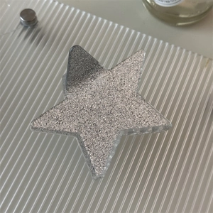Star-shaped hair claw clip in silver glitter finish on a ripple surface