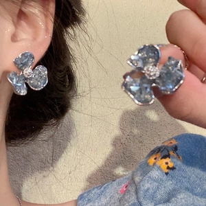 Gros plan sur les boucles d'oreilles fleur en cristal bleu et la bague assortie