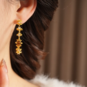 Detail showing vintage gold-plated earrings with tiger eye stone and white zircon