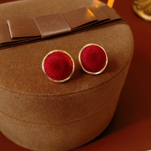 Detail of red velvet round stud earrings with gold trim on a brown jewelry gift box