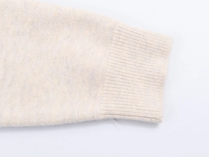 Detailed macro view of cream knitted cardigan cuffs with premium ribbed texture