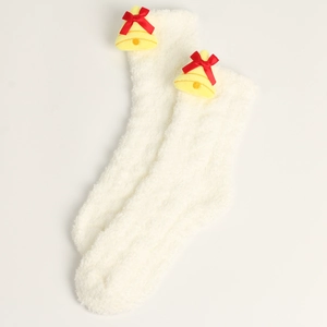 Detail von weißen Plüschsocken mit festlicher gelber Glocke und roter Schleifendeko