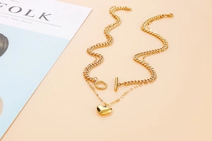 Detail of layered gold titanium necklace with chunky chain, heart pendant and OT clasp