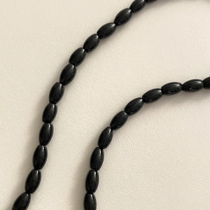Detailed macro view of glossy black onyx olive beads on a 925 sterling silver necklace