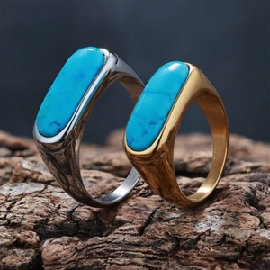 Macro shot of gold and silver turquoise rings on dark bark with brushed metal texture