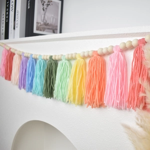 Detailed view of colorful boho wooden bead garland with tassels hanging on a fireplace