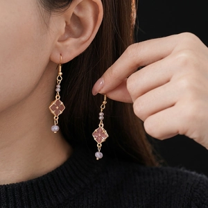Vintage gold dangle earrings with purple flower crystals worn by a model in a side view