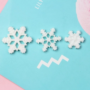 Glittery white resin snowflakes in three sizes for DIY Christmas crafts on pastel background