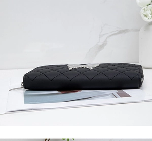 Side view of black quilted leather wallet with silver butterfly ornament and zipper