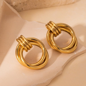 Detailed close-up of 18K gold-plated interlocking hoop earrings on stone background