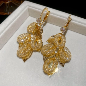 Detailed close-up of golden leaf tassel earrings with sparkling zircon inlay and hollow mesh