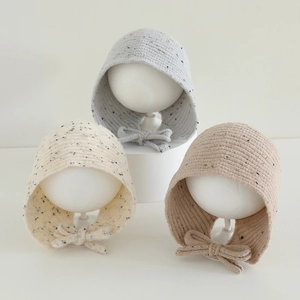 Détail de bonnets en maille chinée avec cordons et nœuds pour enfants et bébés