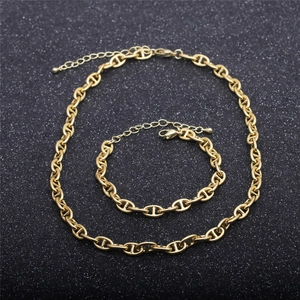 Detailed view of golden anchor link necklace and bracelet set on black background