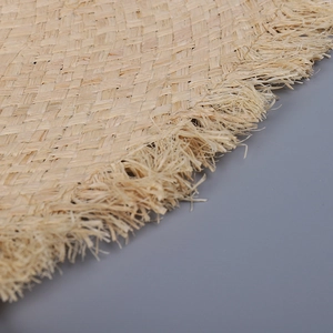 Close-up of natural raffia straw hat edge with dense fringes and tight woven texture